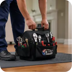 A technician lifting a black tool bag filled with various hand tools.